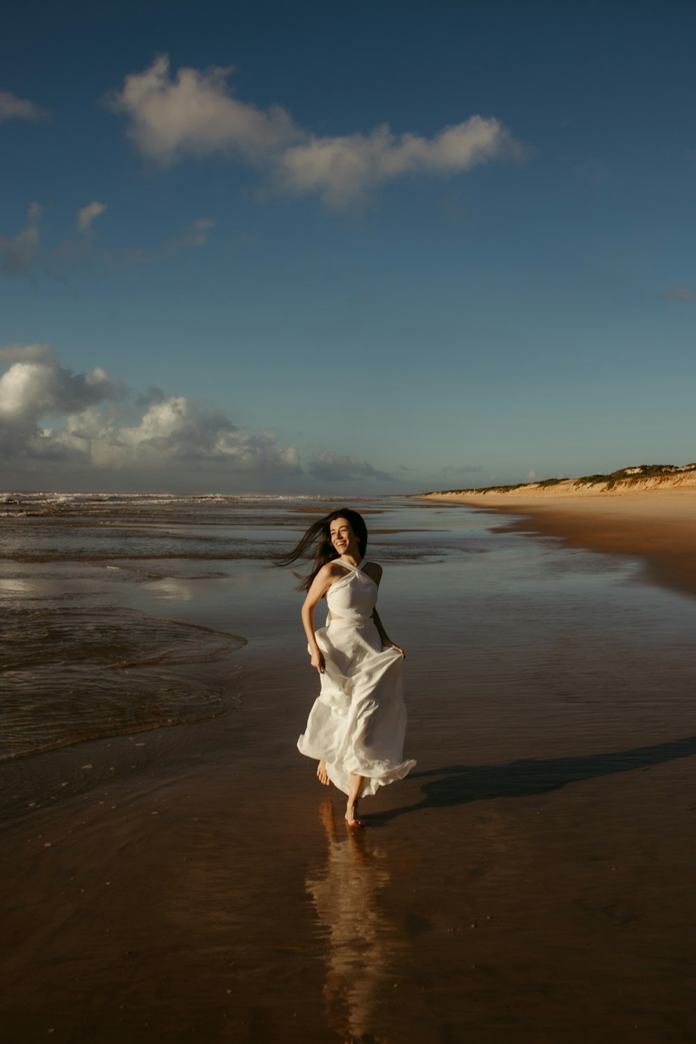 a woman in a white dress is walking on the beach