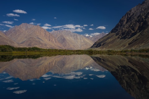 the mountains are reflected in the still water of the lake