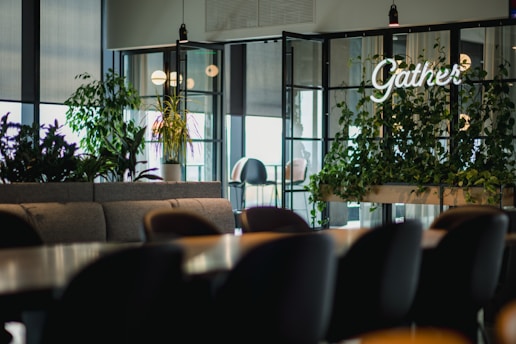 A welcoming community gathering in a bright, green meeting space surrounded by nature.