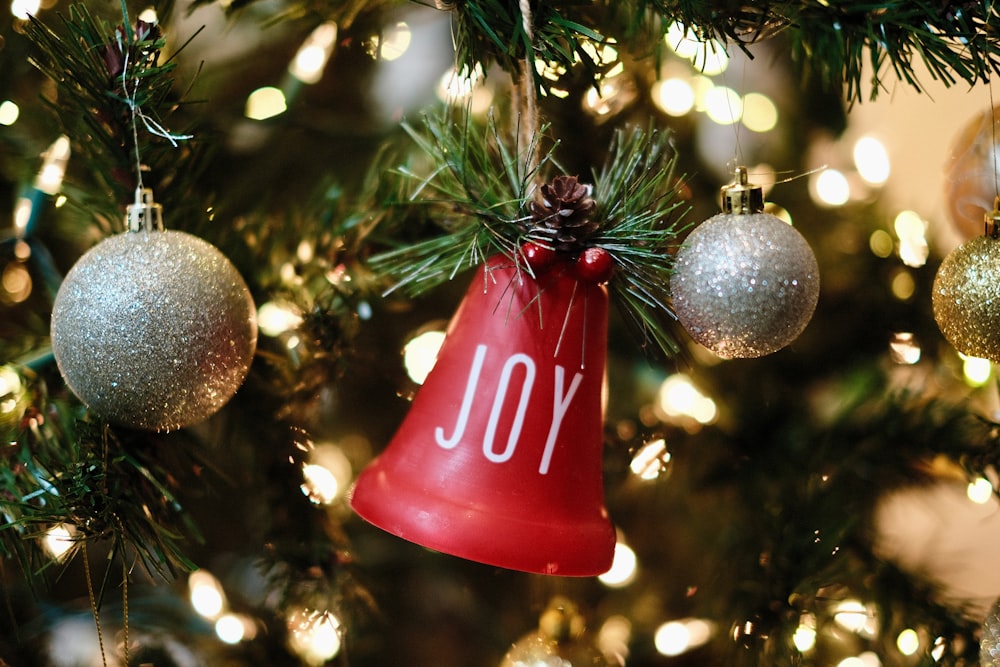 a red bell ornament hanging from a christmas tree