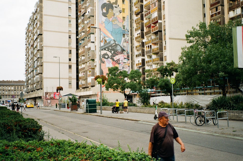 a man walking down a street next to tall buildings