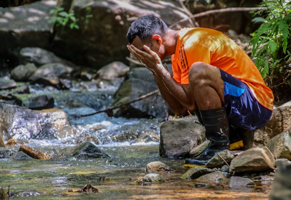 a man kneeling down next to a river