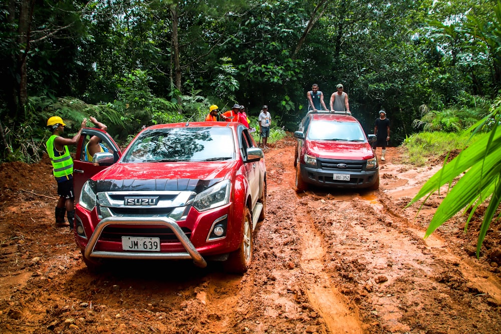 a couple of red trucks driving down a muddy road