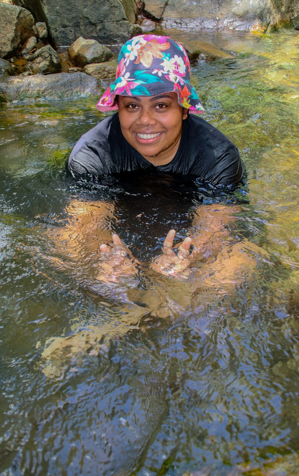 una mujer parada en un río con las manos en el agua