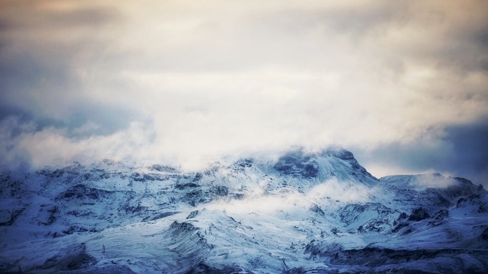 a mountain covered in snow under a cloudy sky