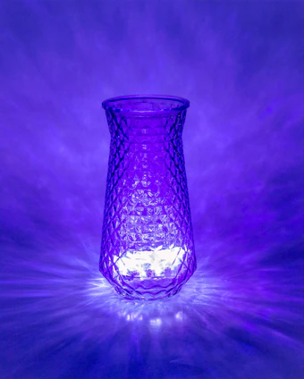A vibrant 3D-printed geometric vase glowing under warm light in a cozy studio setting