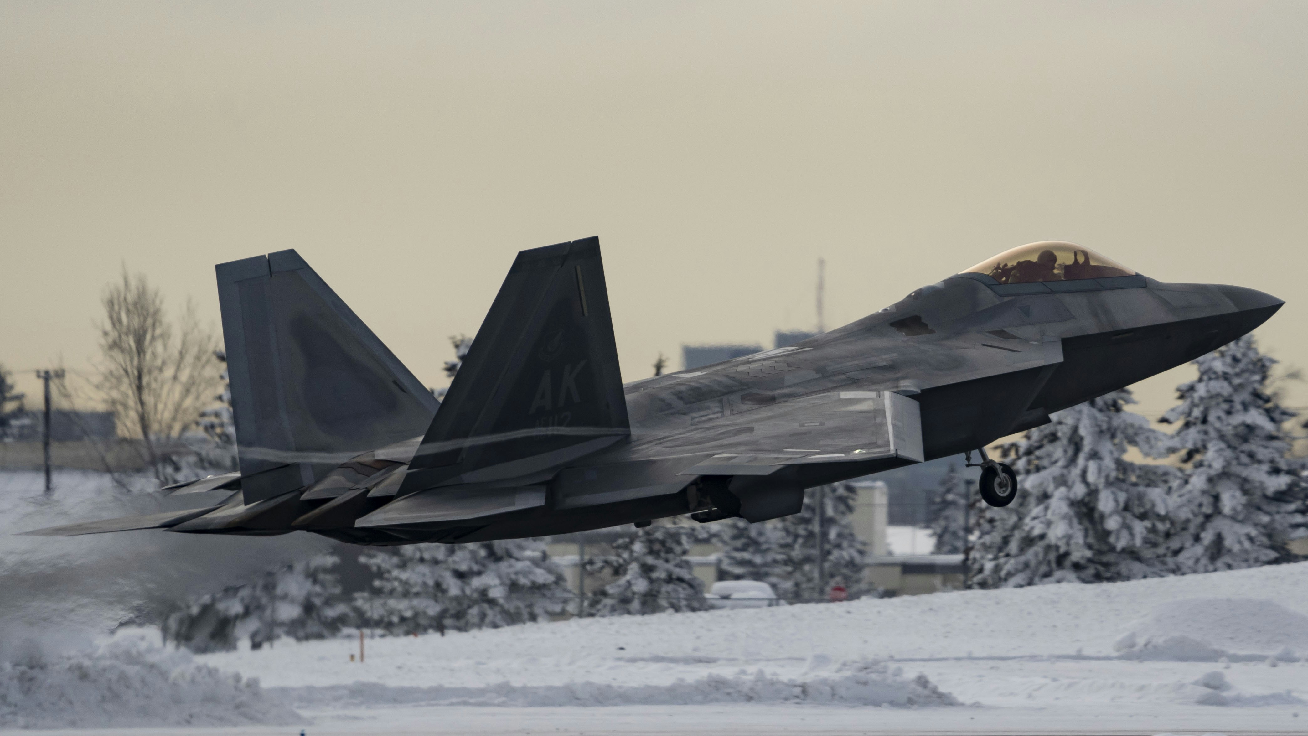 a fighter jet taking off from an airport runway, A U.S. Air Force F-22 Raptor assigned to the 3rd Wing takes off above Joint Base Elmendorf-Richardson