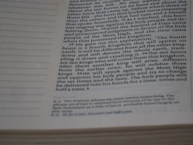 A close-up of a printed page with text from a book. The text appears to be from a religious or historical text, possibly a Bible. The page is filled with text, with some italicized or bolded to emphasize certain parts. There is a column of lined spaces on the left side for notes or annotations.
