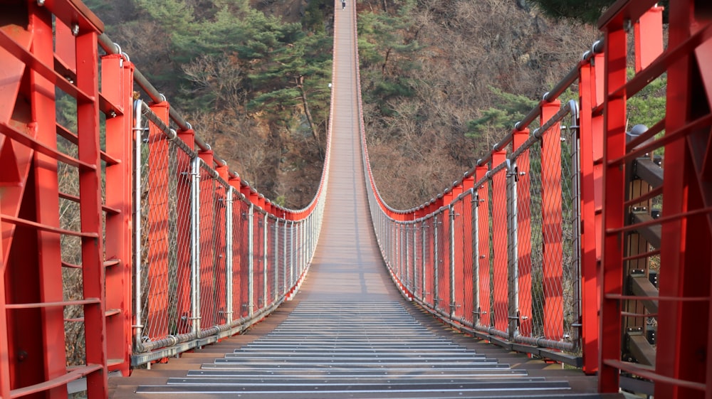 a long red bridge with metal railings over a river