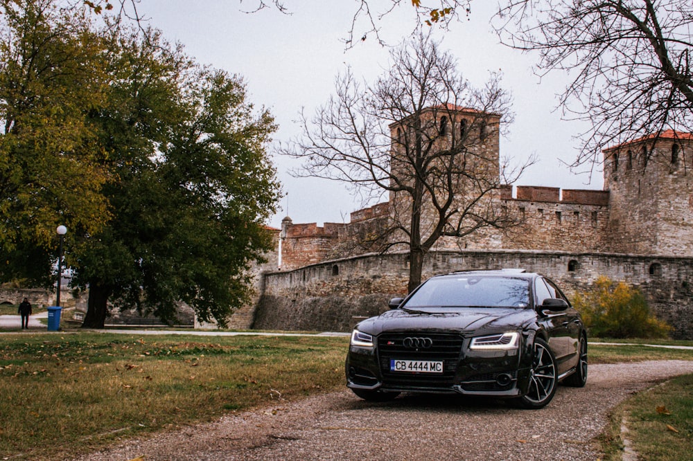a black car parked in front of a castle