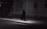 Nighttime street scene with a private investigator following a person discreetly