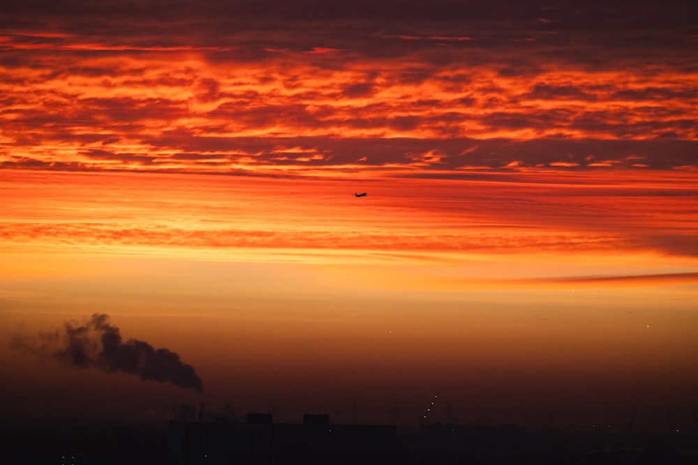 a red sky with a plane flying in the distance