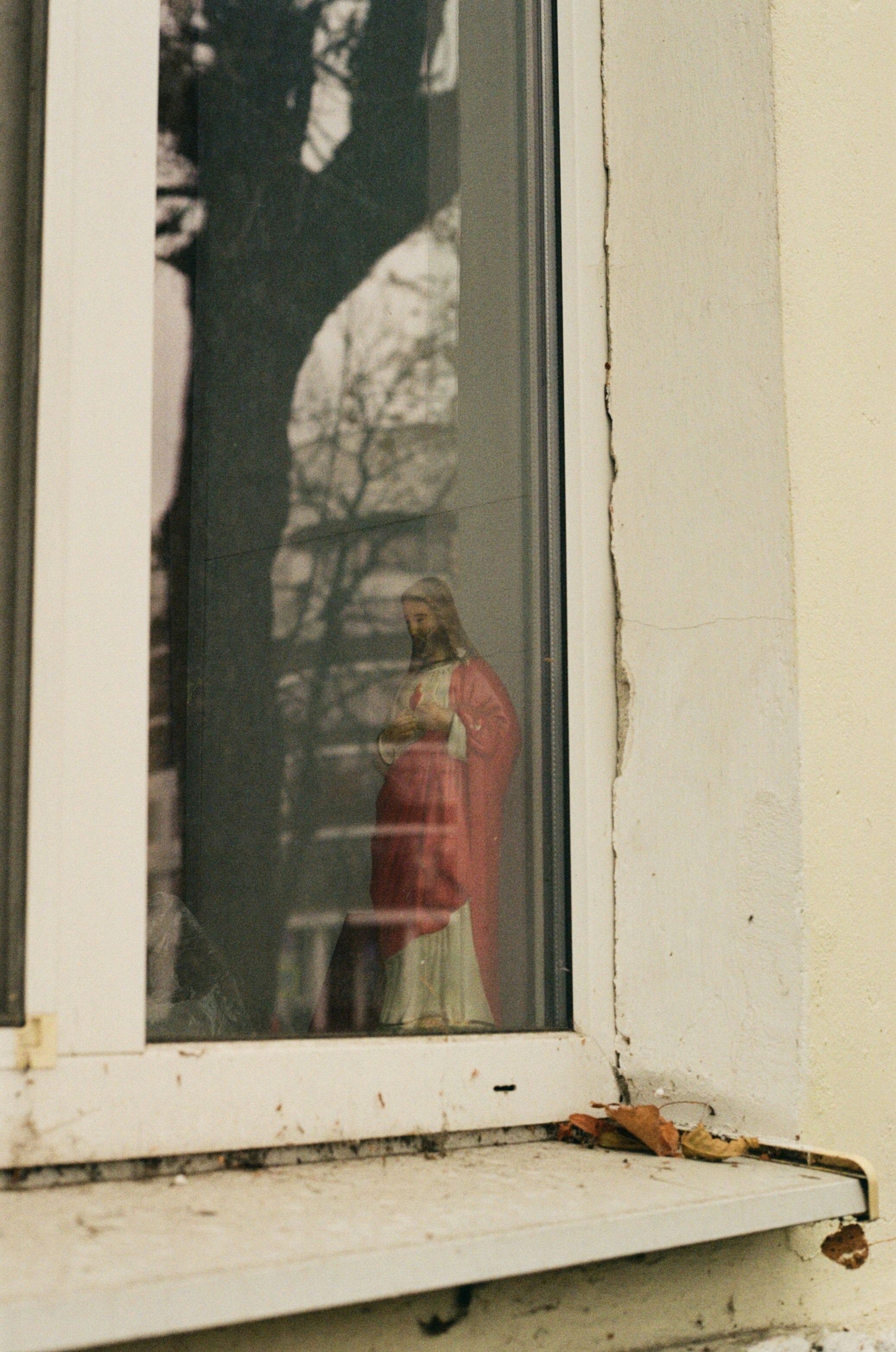 a statue of a person in a red coat is seen through a window