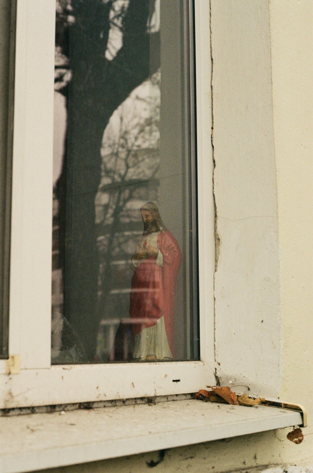 a statue of a person in a red coat is seen through a window