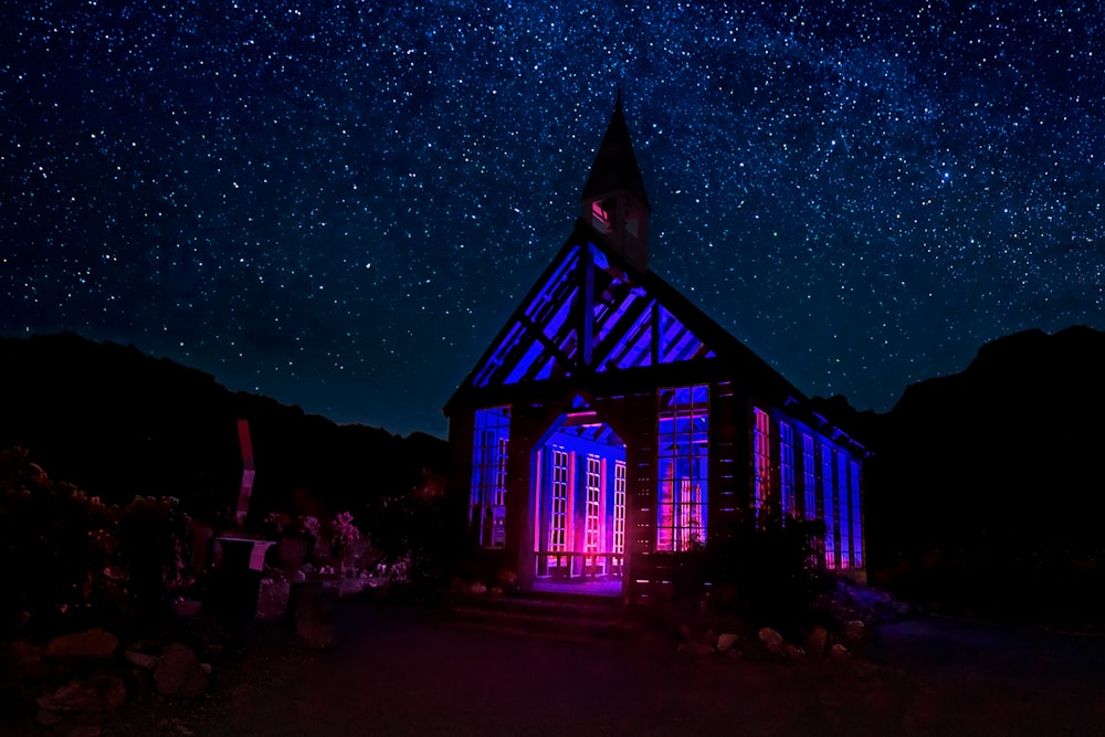 um edifício iluminado com uma torre de relógio sob um céu noturno cheio de estrelas