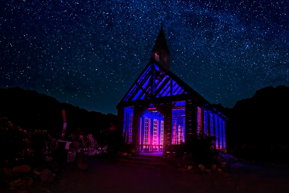 a lit up building with a clock tower under a night sky filled with stars