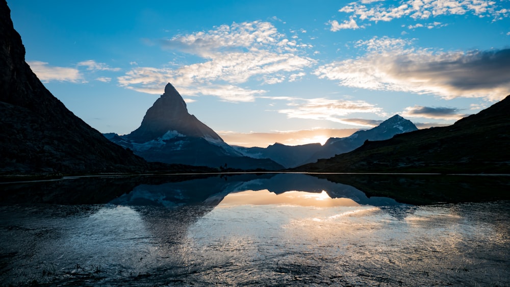 Ein Gebirgszug spiegelt sich im stillen Wasser eines Sees