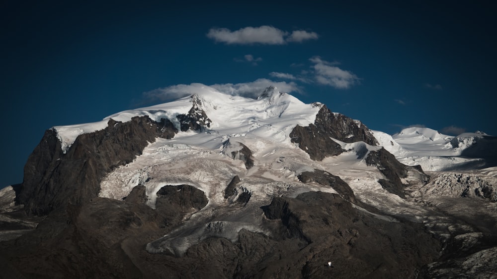 a large mountain covered in snow under a blue sky