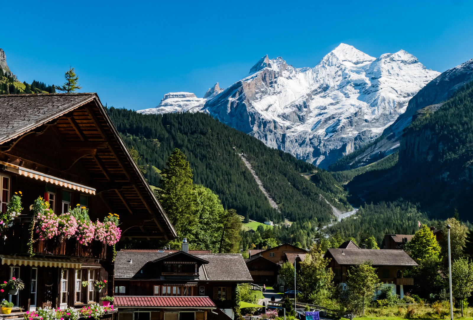 Village de montagne au pied d'une chaîne de sommets, en été (image d'illustration)