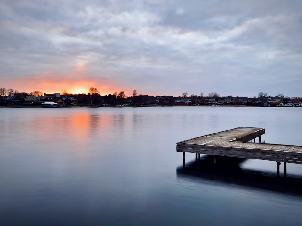 a dock sitting on top of a lake under a cloudy sky