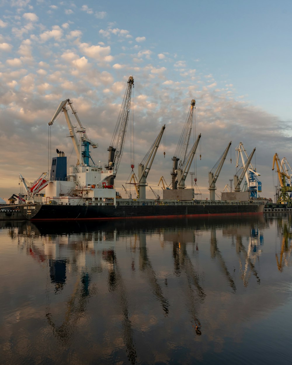 a large boat in the water with cranes in the background