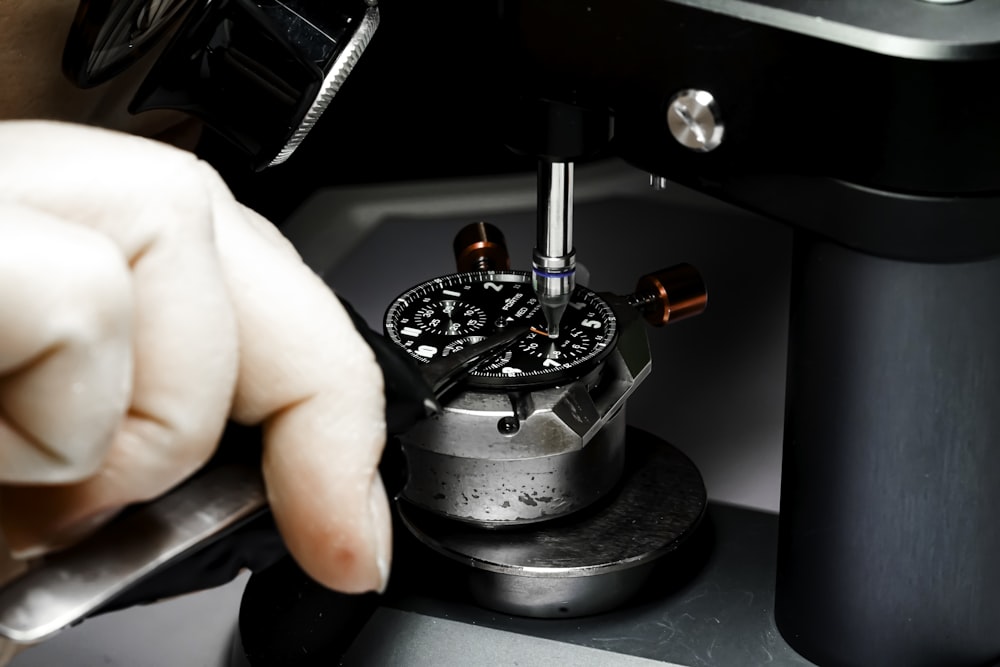 a person is working on a watch in a machine