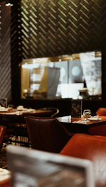 Cozy interior of noirflame with dark elegant tones and warm lighting highlighting a table set with smashed burgers and cocktails.