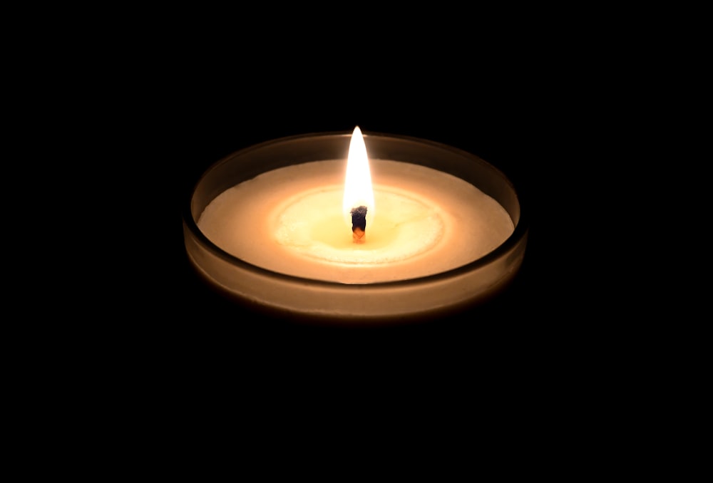 a lit candle in a glass bowl on a black background