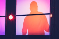 A silhouette of regal rhythm against soft stage lights, the rainbow hues subtly glowing in the background.