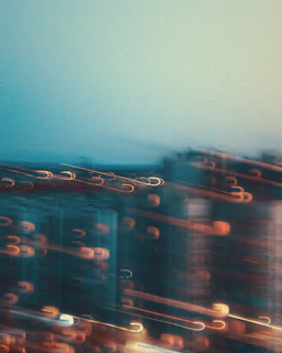 A monochrome shot of a cityscape at dusk with blurred moving cars creating light trails.