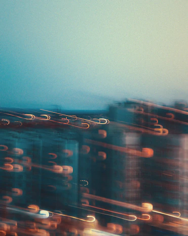 A monochrome shot of a cityscape at dusk with blurred moving cars creating light trails.