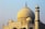 A large, intricately designed marble structure with a prominent domed roof. The architecture features a combination of arches, columns, and intricate inlay work, typical of Mughal design. Two minarets stand adjacent to the dome, showcasing symmetry and detailed craftsmanship.
