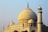A large, intricately designed marble structure with a prominent domed roof. The architecture features a combination of arches, columns, and intricate inlay work, typical of Mughal design. Two minarets stand adjacent to the dome, showcasing symmetry and detailed craftsmanship.