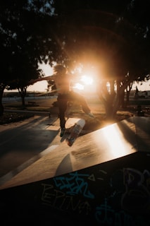 Urban skateboarder performing a trick on a graffiti-covered ramp at sunset in Granada.