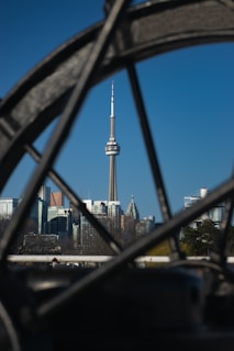 A vibrant street scene in Toronto with the CN Tower in the background under a clear blue sky.