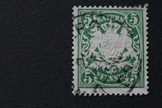 A vintage green postage stamp with a crowned emblem in the center and the word 'BAYERN' at the top. The denomination of 5 is printed in each corner of the stamp, with 'PFENNIG' at the bottom. The design includes intricate patterns and a cancelation mark indicating prior use.