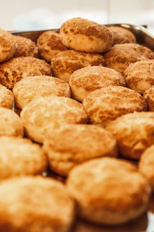 Freshly baked bread rolls with a golden crust, arranged on a wooden board with a sprinkle of flour.
