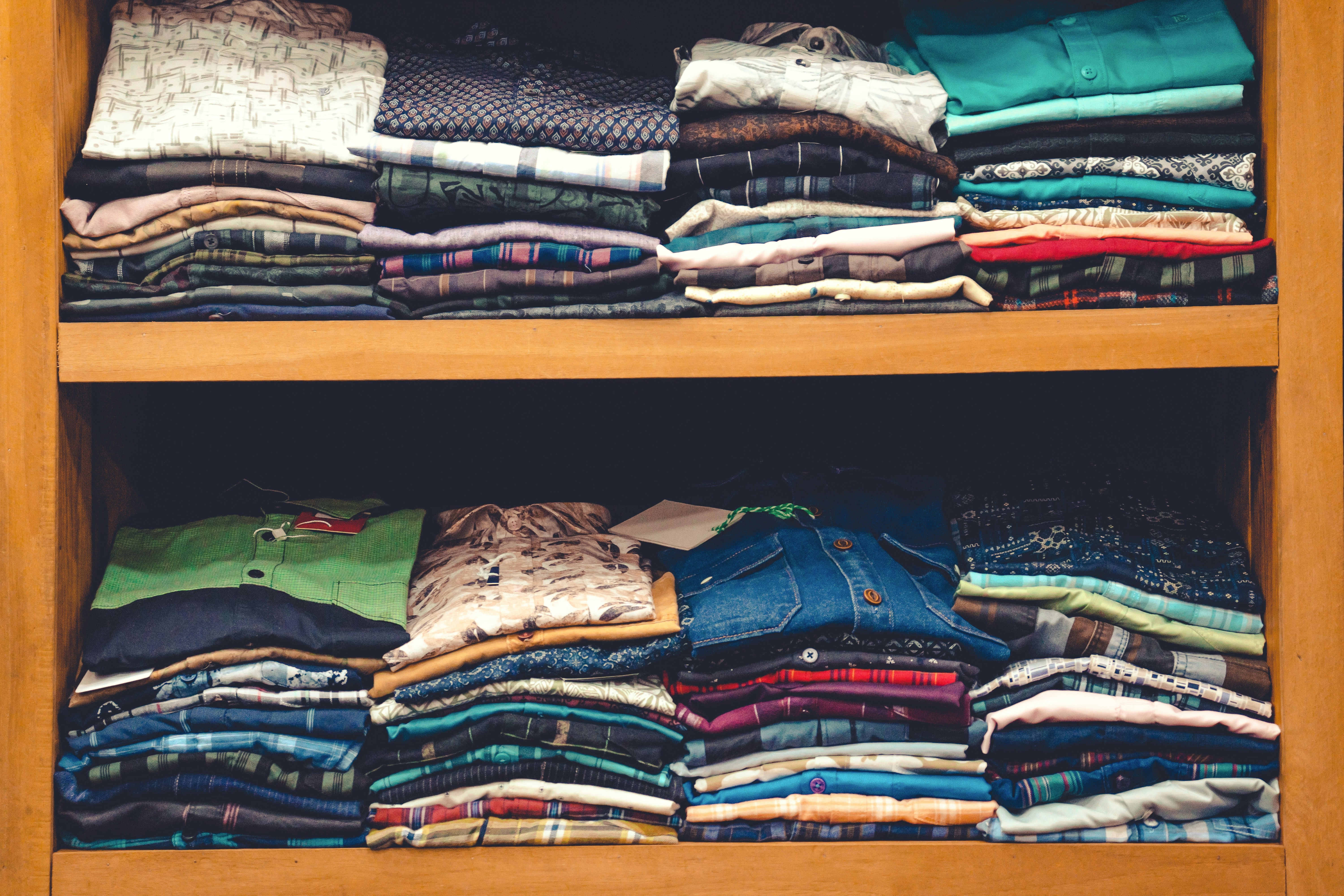 a wooden shelf filled with lots of folded shirts