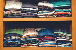 a wooden shelf filled with lots of folded shirts