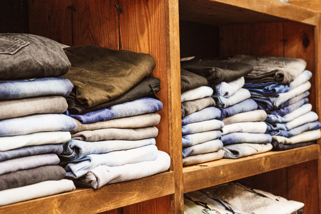 Prateleira de madeira com roupas dobradas por cor