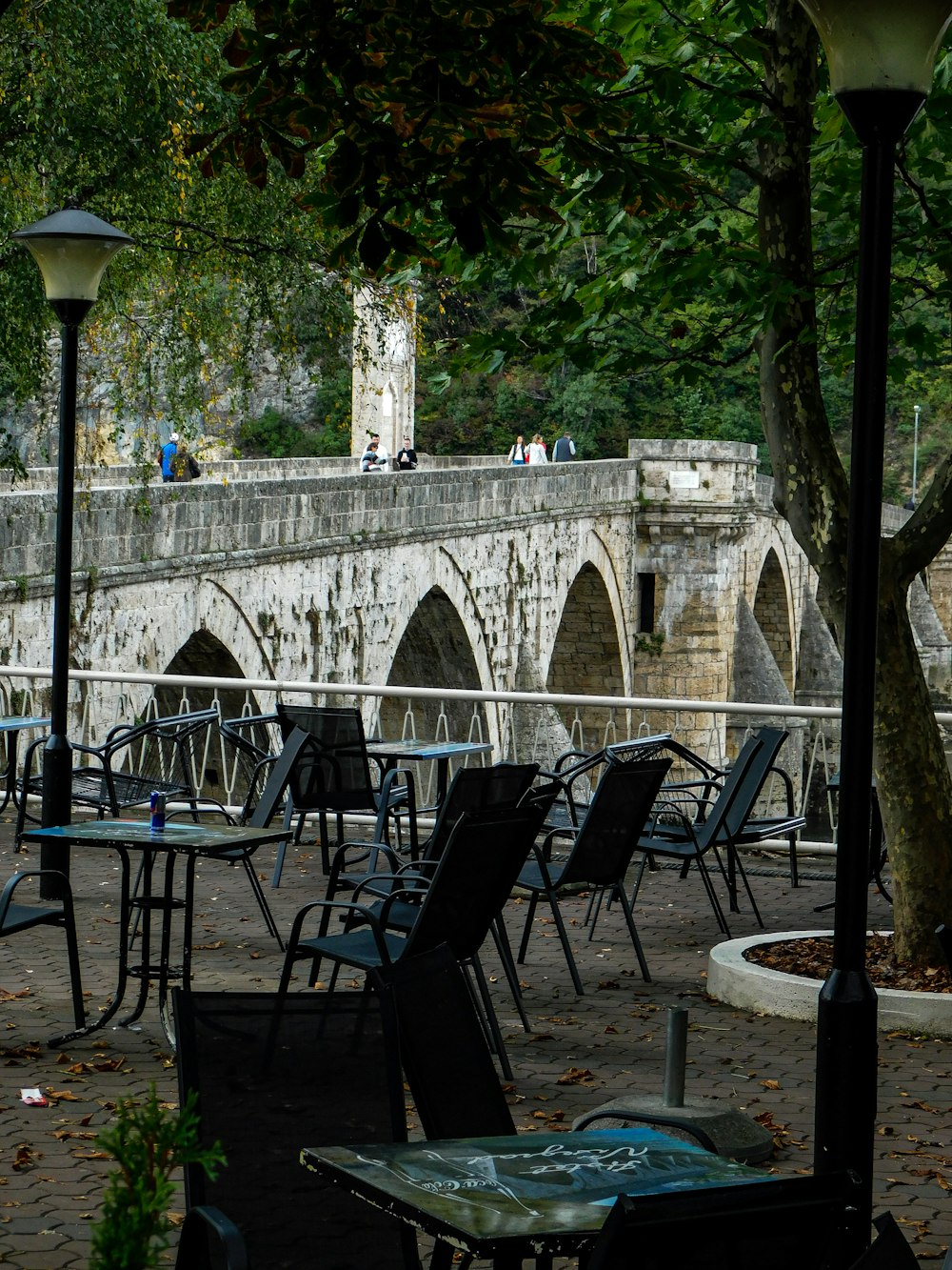 a bunch of tables and chairs that are by a bridge