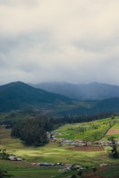 A serene view of the rolling valleys and organic farms stretching into the distance under a cloudy sky.