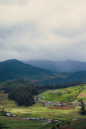 A serene view of the rolling valleys and organic farms stretching into the distance under a cloudy sky.