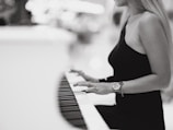 a woman in a black dress playing a piano