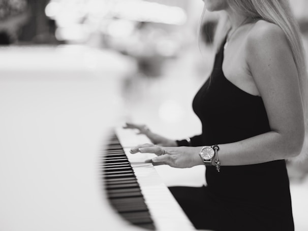 a woman in a black dress playing a piano