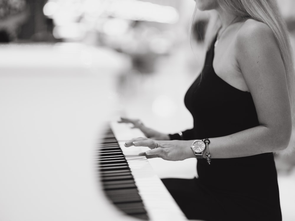 a woman in a black dress playing a piano