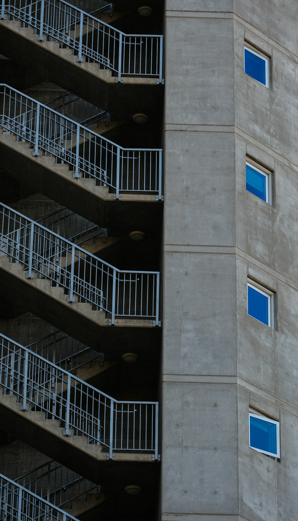 a tall building with balconies and blue windows