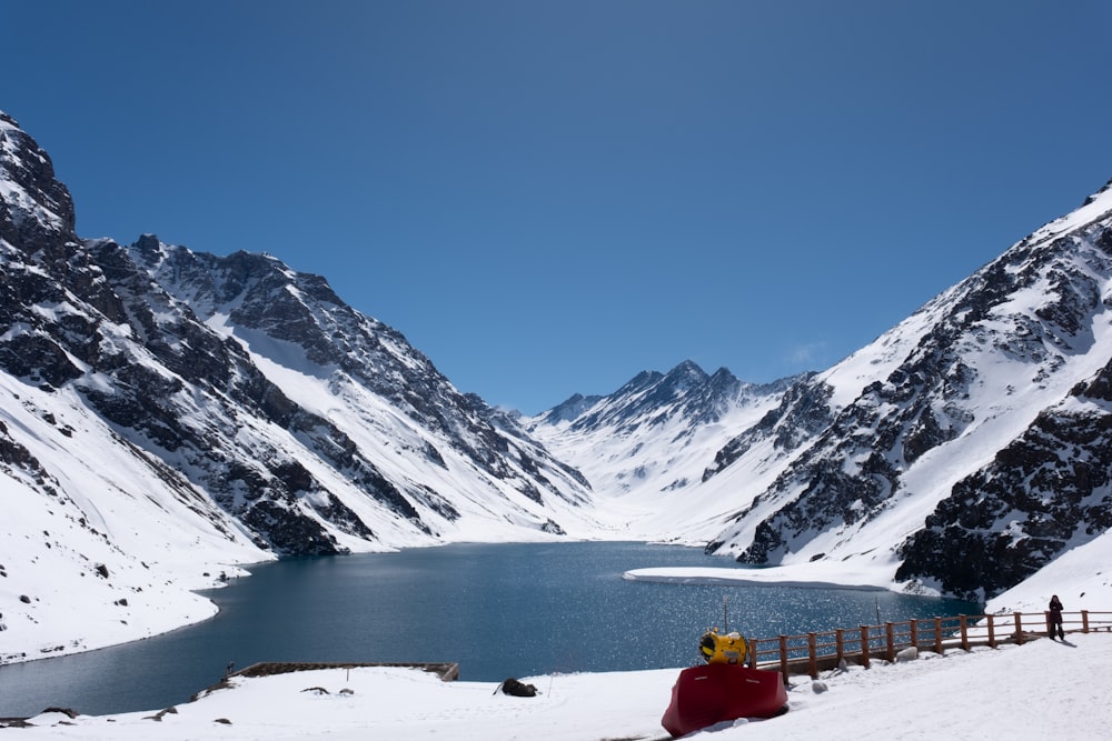 a lake surrounded by snow covered mountains under a blue sky