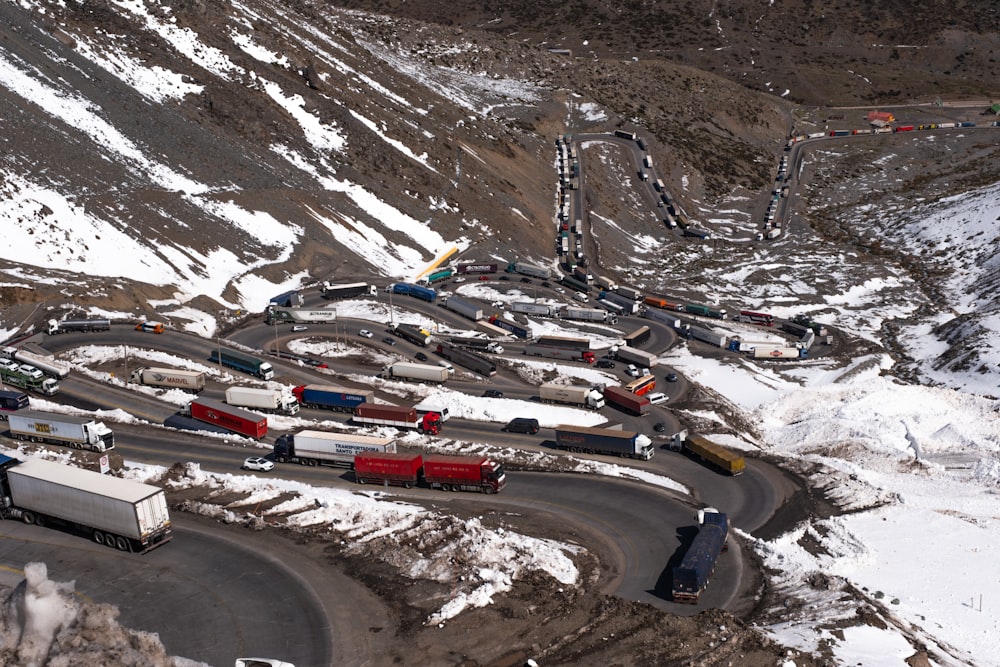 a long line of trucks driving down a snow covered road