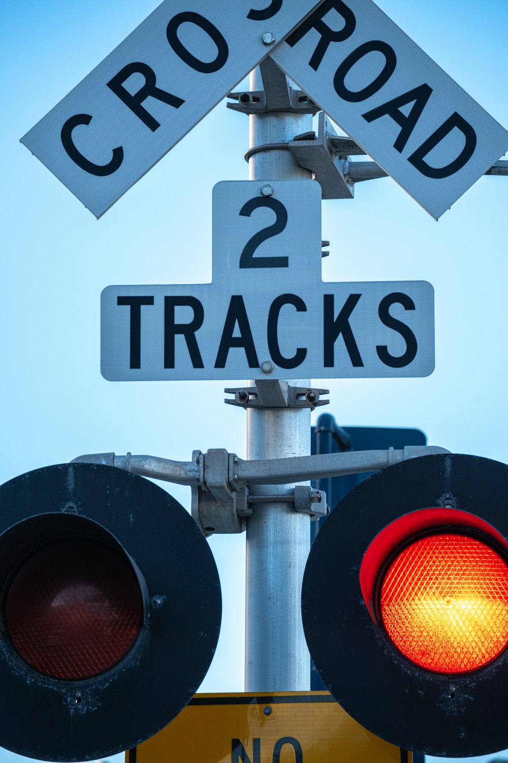 a red traffic light sitting below a railroad crossing sign